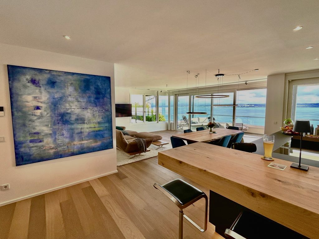 Modern ocean-view living space with abstract art and wooden accents.