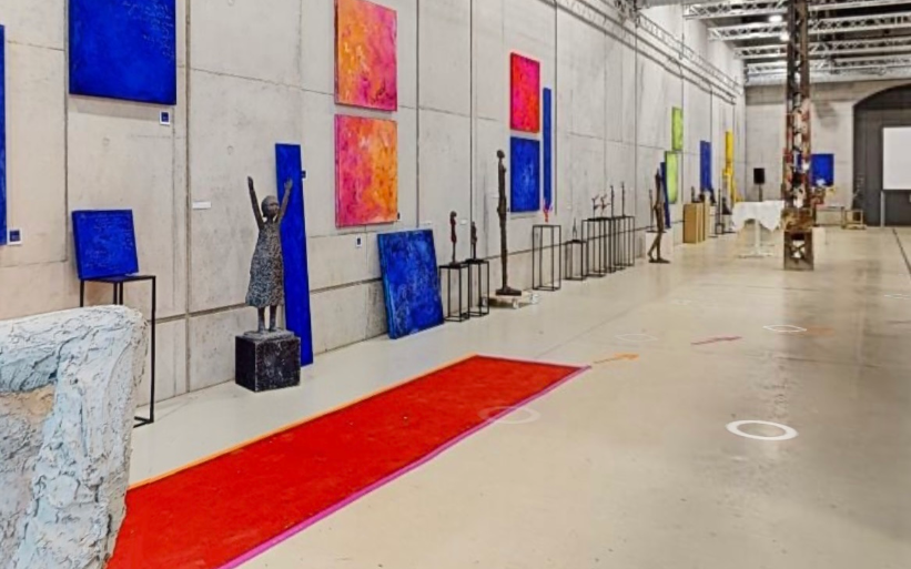 Art gallery with colorful abstract paintings, sculptures, and a red carpet on the floor.