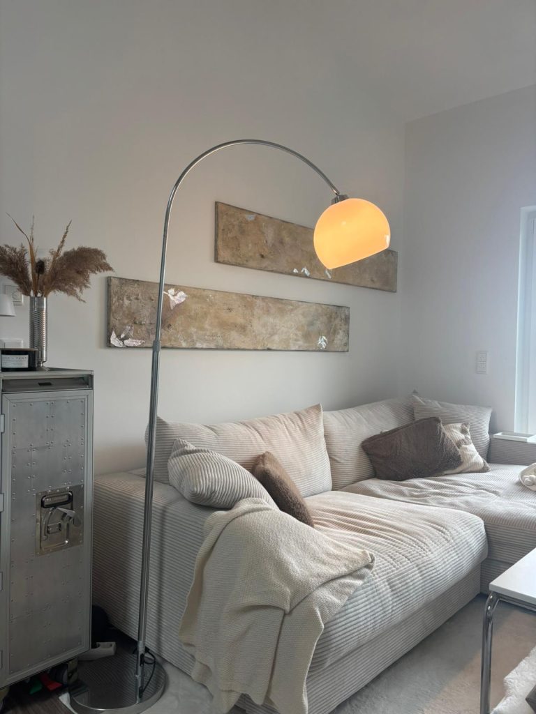 Gemütlicher Wohnbereich mit beigem Sofa, Wanddekoration und warmem Licht.